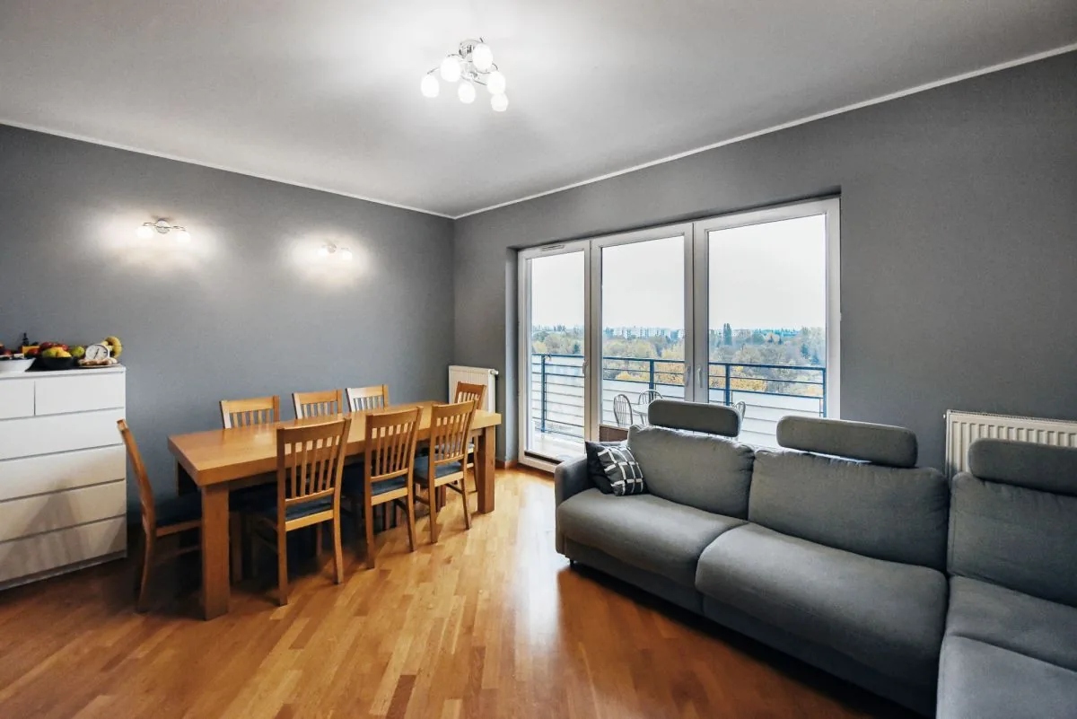 Salon z jadalnią i wyjściem na balkon, szare ściany, drewniana podłoga