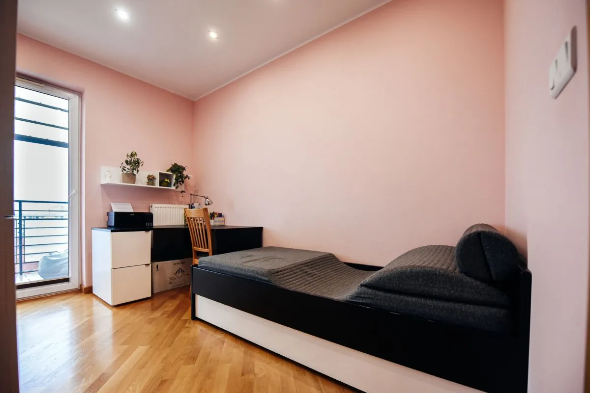 Sypialnia z biurkiem, różowe ściany, wyjście na balkon