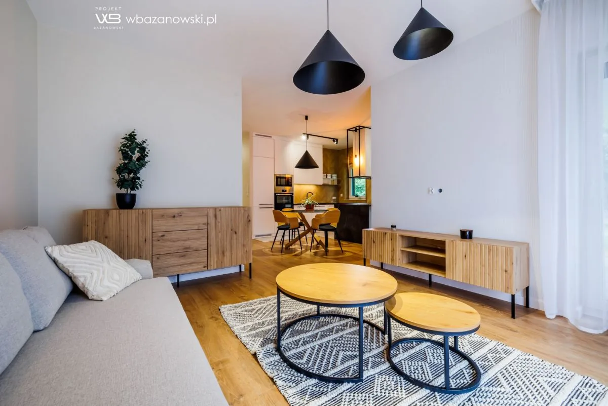 Salon z sofą, drewnianą komodą i okrągłymi stolikami