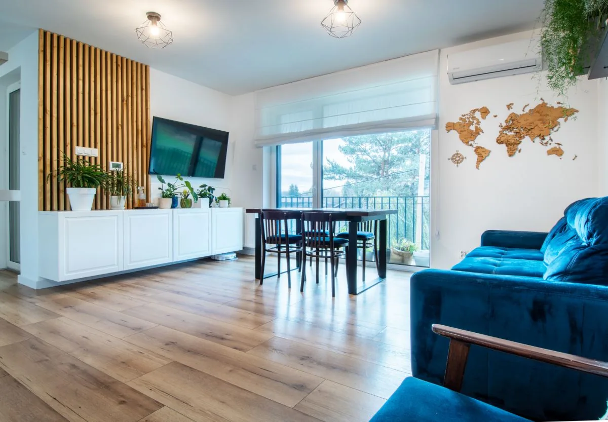 Salon z granatową sofą, ażurową ścianką z drewna i wyjściem na balkon