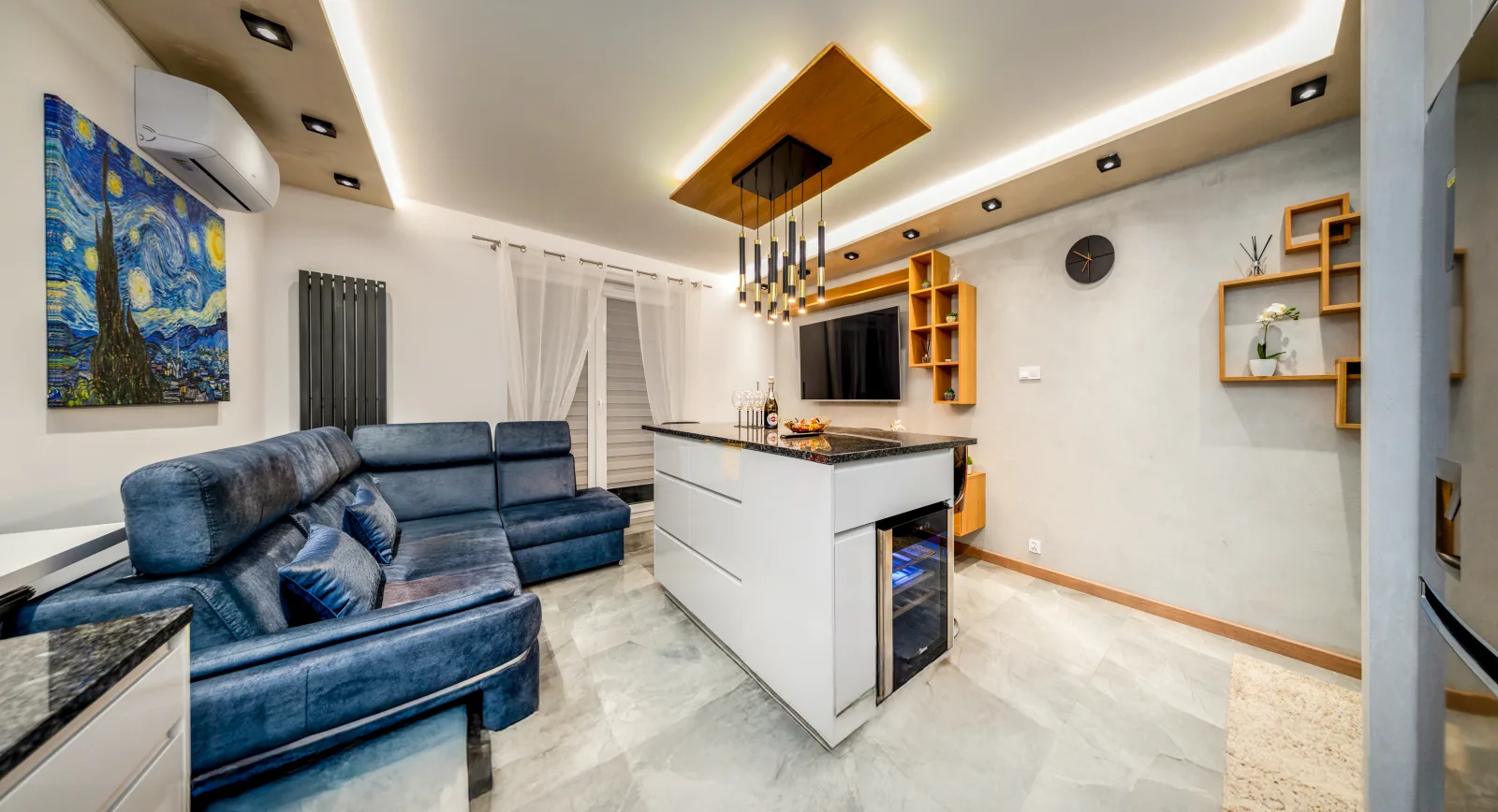 Salon z niebieską sofą i wyspą kuchenną