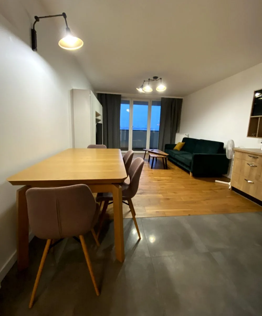 Jadalnia z drewnianym stołem przy wyjściu na balkon