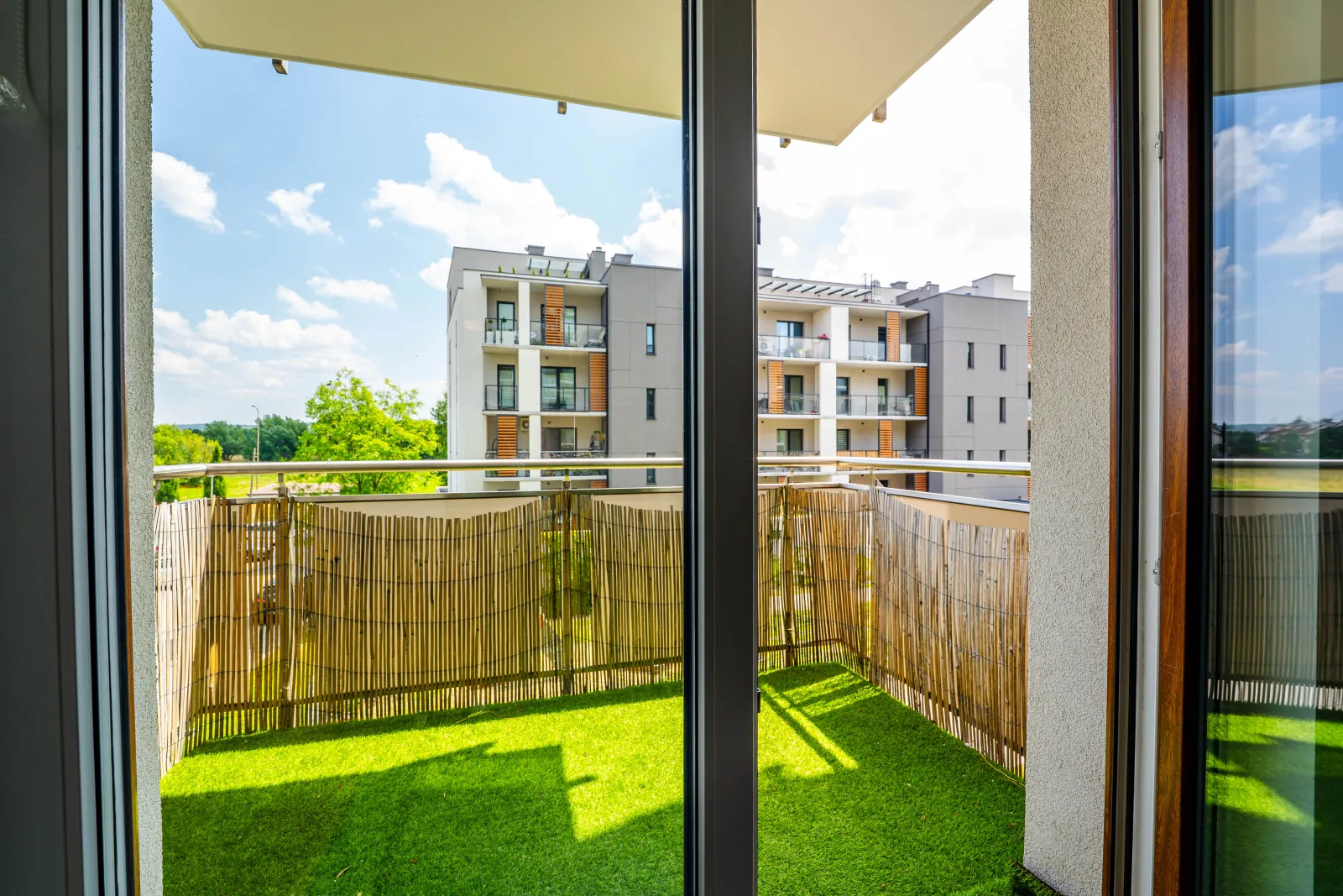 Balkon ze sztuczną trawą i widokiem na osiedle